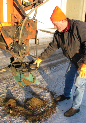 Photo of Scott Rennecke inspecting salt spinner on a plow truck.